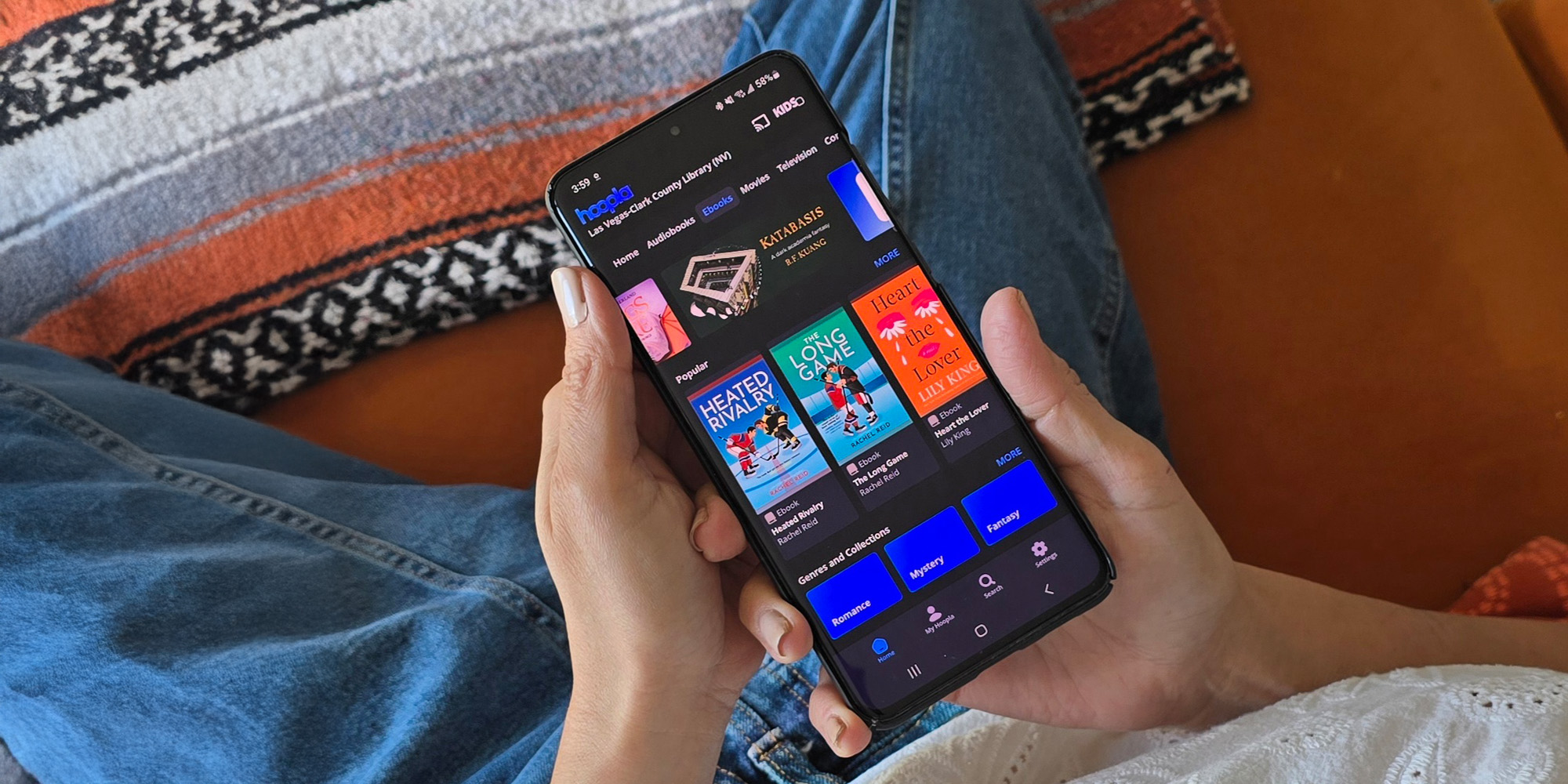 A woman sitting, relaxing on her phone using the Hoopla app.