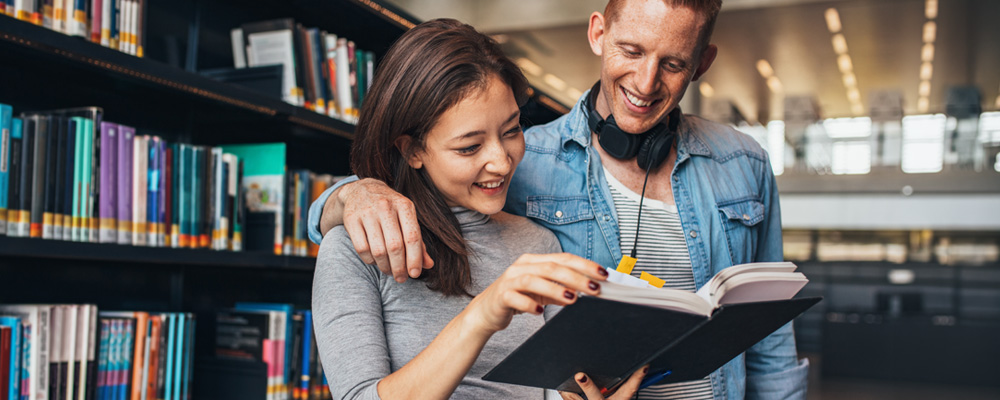 A young couple are browsing books at the library.